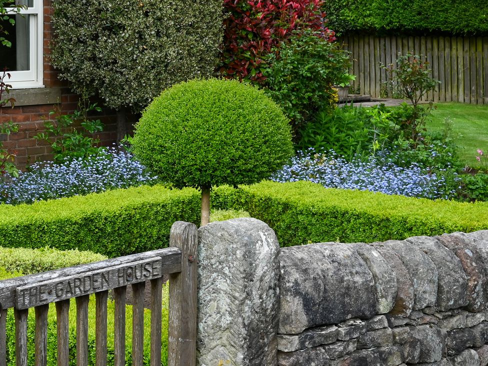 A garden with a stone wall and a gate at The Garden House in Alton