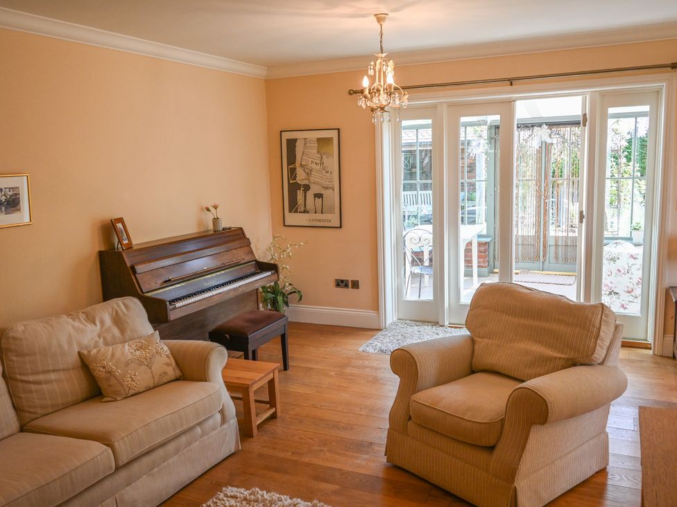 A living room with a piano and an armchair at The Garden House in Alton