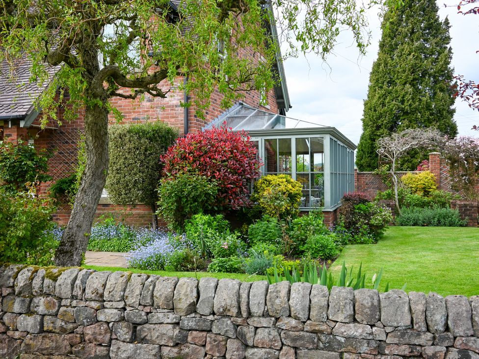 A garden with a greenhouse and flower beds at The Garden House in Alton