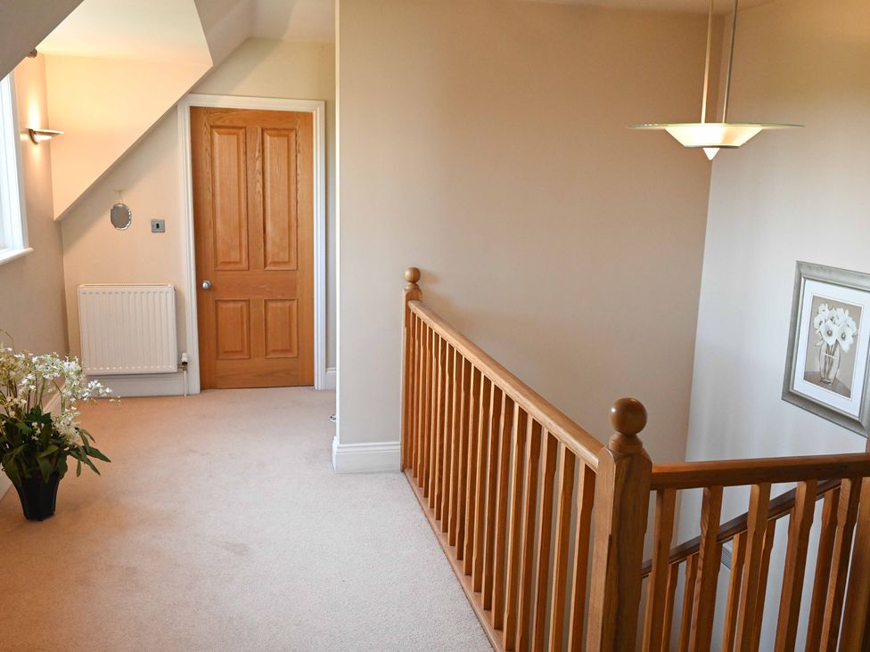 A hallway with a door and stair railing at The Garden House in Alton