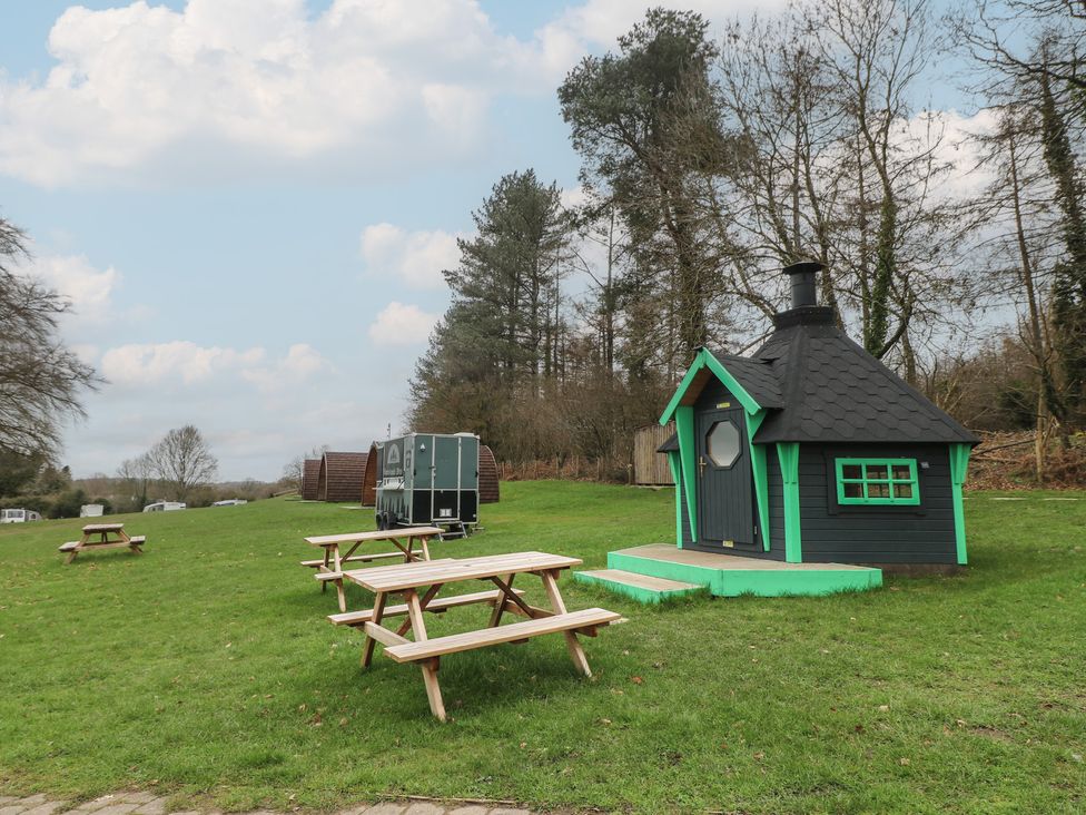 A cabin with a chimney and picnic tables in an outdoor area at Bracelands - Cosy Pod 1 Coleford