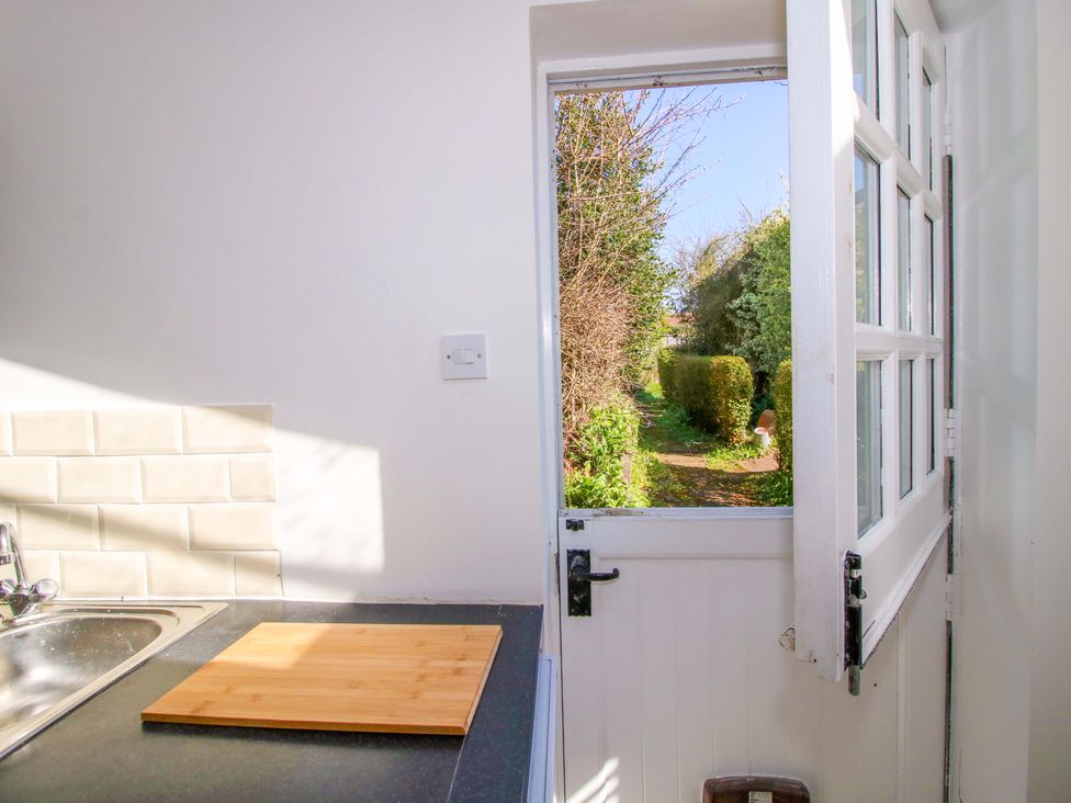 A kitchen with a cutting board and an open door leading to a garden at Cheshire Views in Malpas