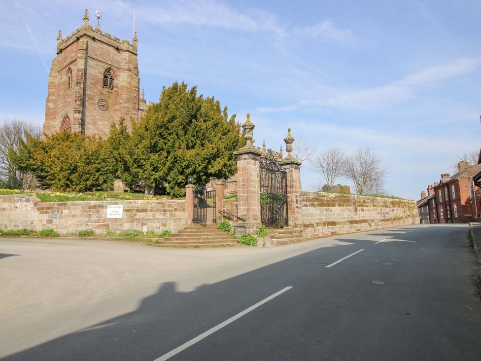 A church with a stone wall and gate along the road at Cheshire Views in Malpas