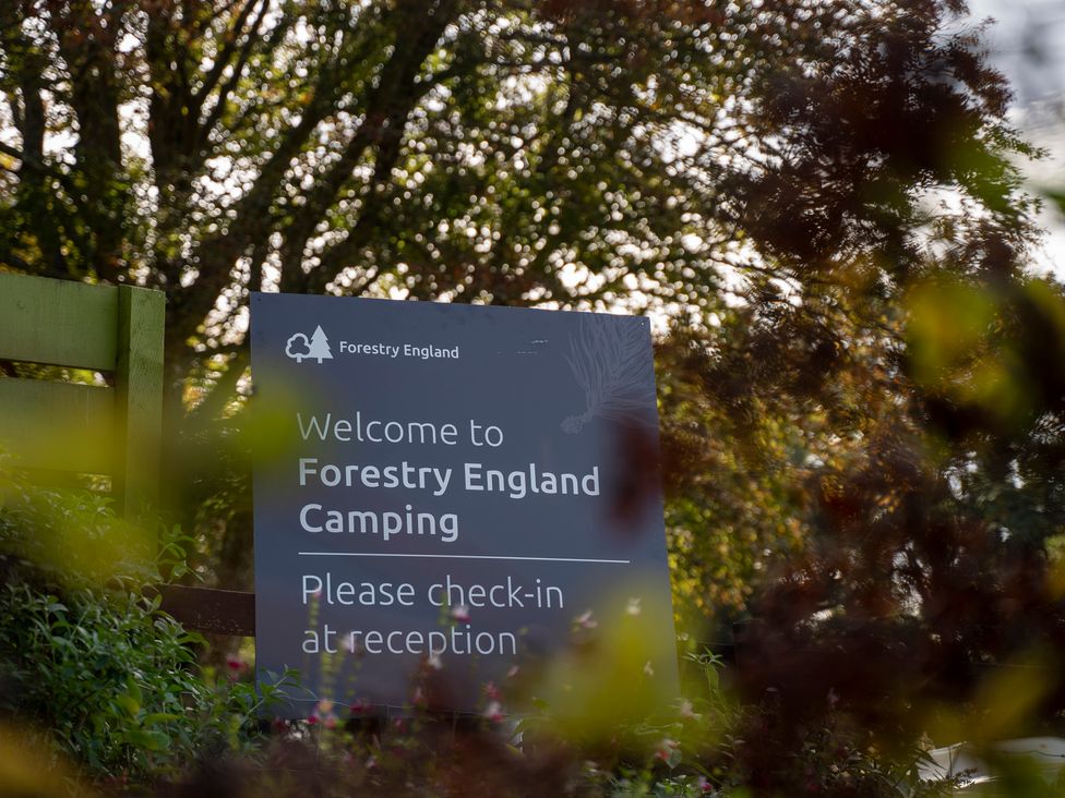 A welcome sign for Forestry England Camping surrounded by trees at Bracelands - Cosy Pod 2 in Coleford