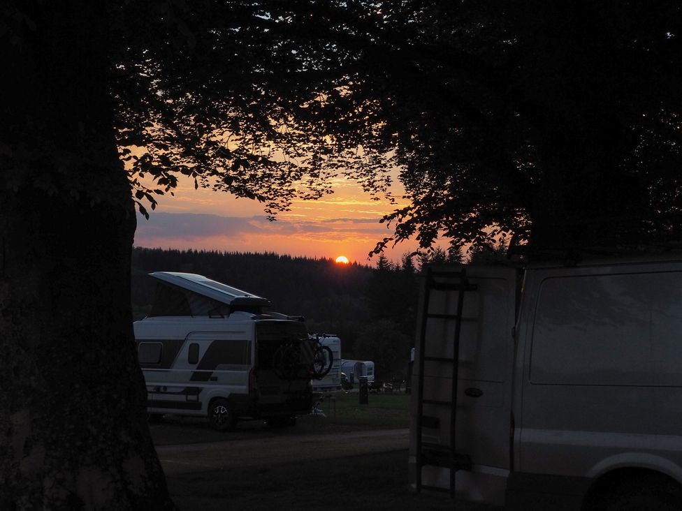 A sunset view with campers and trees at Bracelands - Cosy Pod 3 Coleford