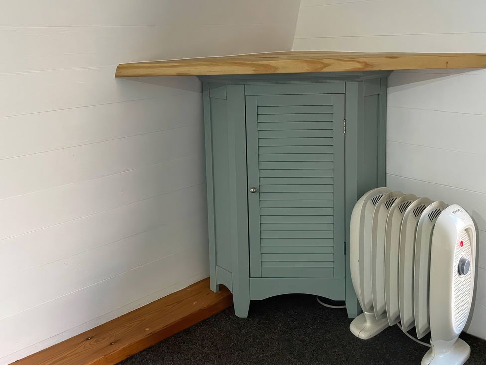 A cabinet with a wooden top and a space heater at Bracelands - Cosy Pod 4, Coleford