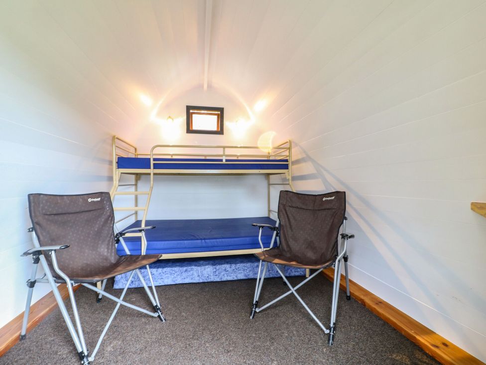 A sleeping area with a bunk bed and two chairs at Bracelands - Cosy Pod 4 in Coleford