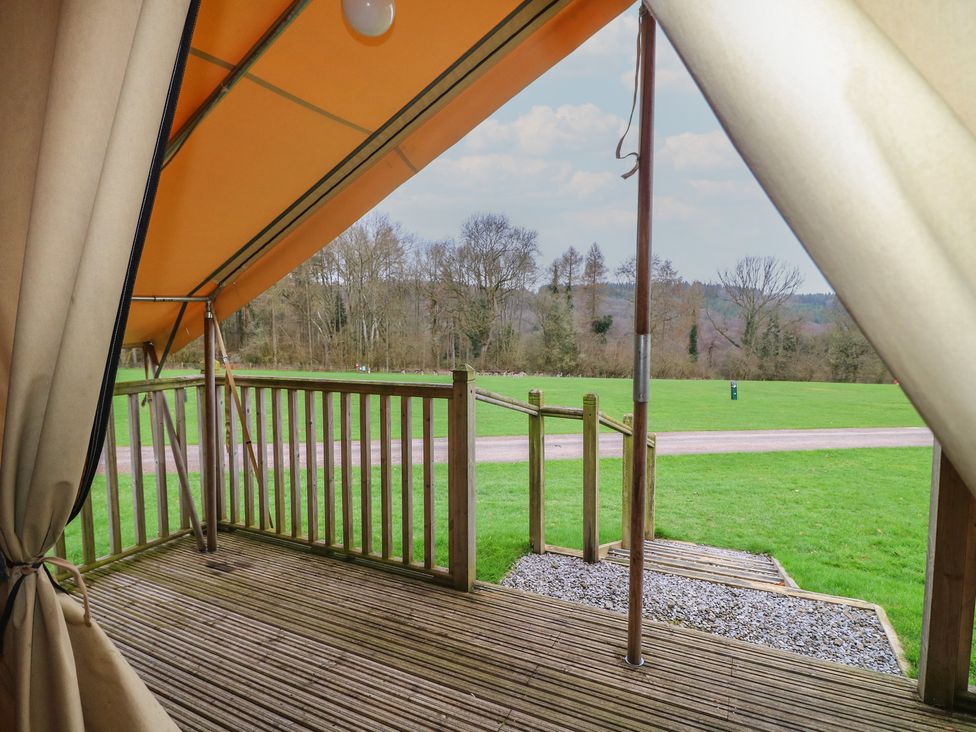 A view from a tent overlooking a deck and grassy area at Bracelands - Safari Tent 1 in Coleford
