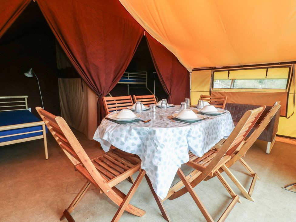 A dining area with wooden table and chairs at Bracelands - Safari Tent 1 in Coleford