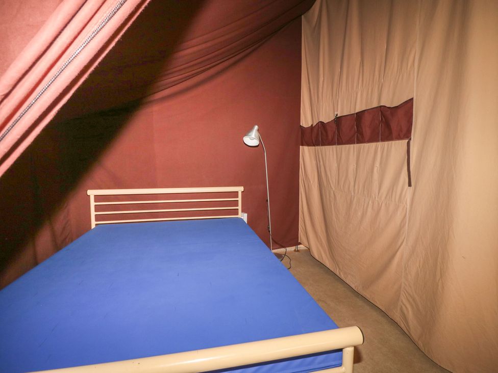 A bedroom with a bed and lamp at Bracelands - Safari Tent 2 near Coleford