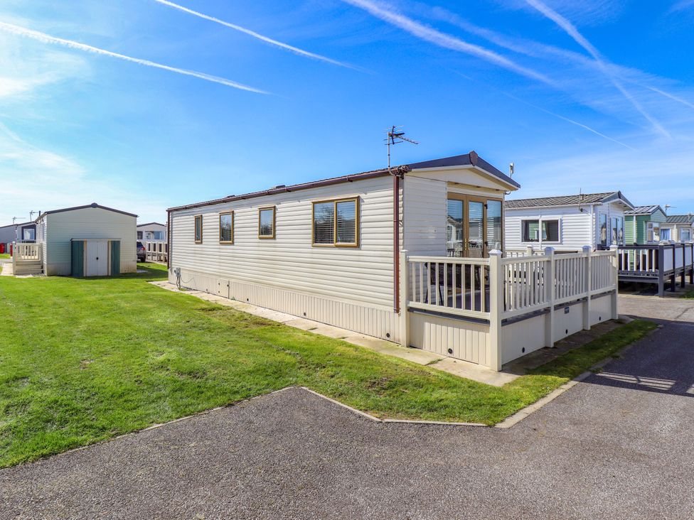A mobile home with a deck and shed at Loopy’s Place - PG178 in Chapel St Leonards