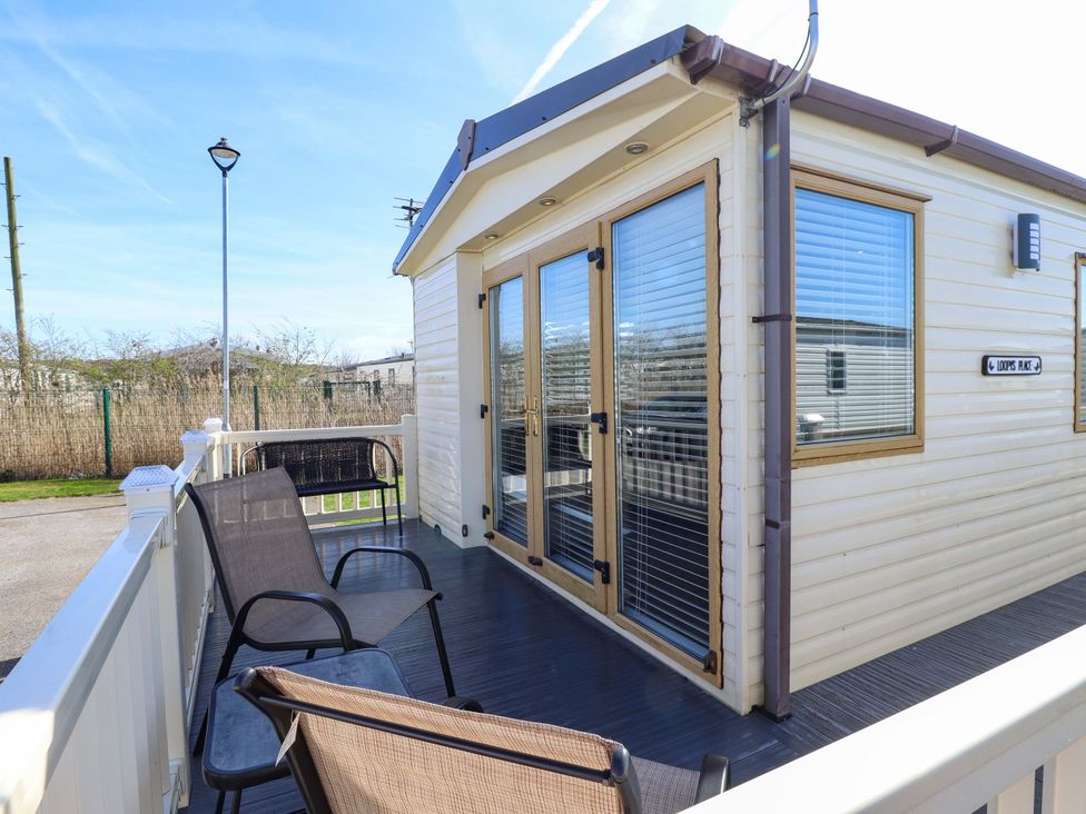 An outdoor deck area with chairs and doors at Loopy’s Place - PG178 in Chapel St Leonards