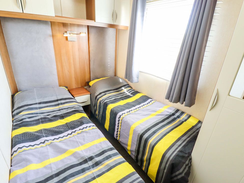 A bedroom with twin beds and a nightstand at Loopy’s Place - PG178 in Chapel St Leonards