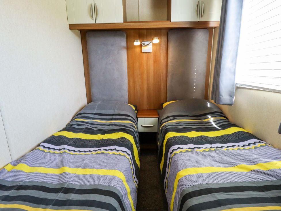 A bedroom with two single beds and a bedside table at Loopy’s Place - PG178 in Chapel St Leonards