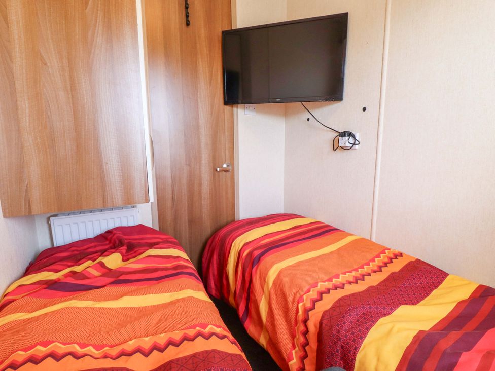 A bedroom with two beds and a television at Loopy’s Place - PG178, Chapel St Leonards