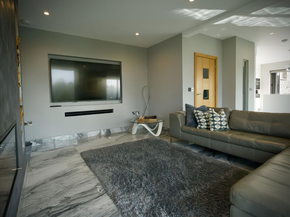 A living room with a television and sofa at Midways in Windermere