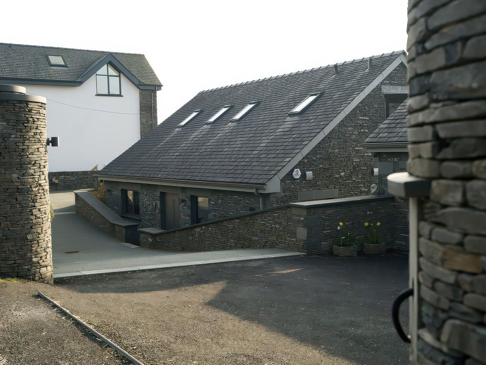 An exterior view of buildings with stone walls and flower pots at Midways Bowness-On-Windermere