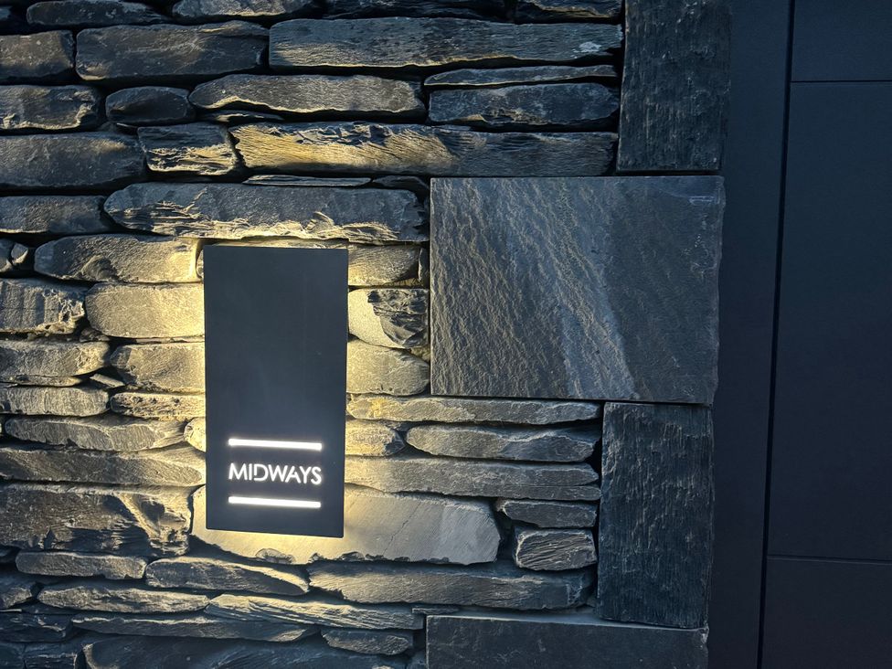 A stone wall with a light fixture and sign at Midways Bowness-On-Windermere