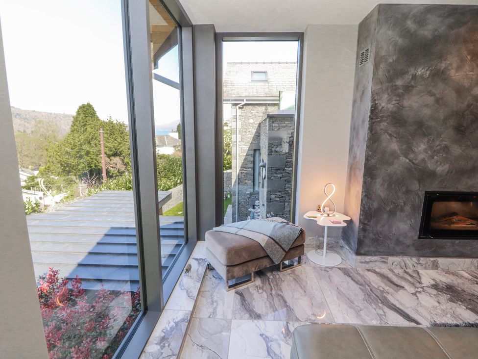 A living room with a fireplace and large windows at Midways in Bowness-On-Windermere