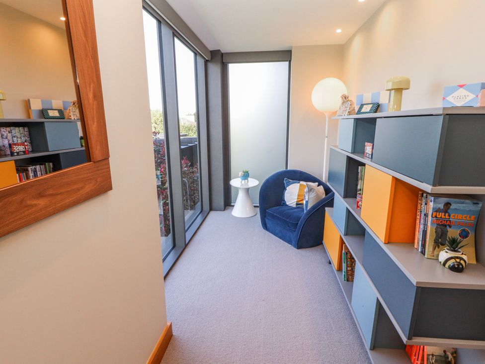 A snug with a blue chair and bookshelf at Midways in Bowness-On-Windermere