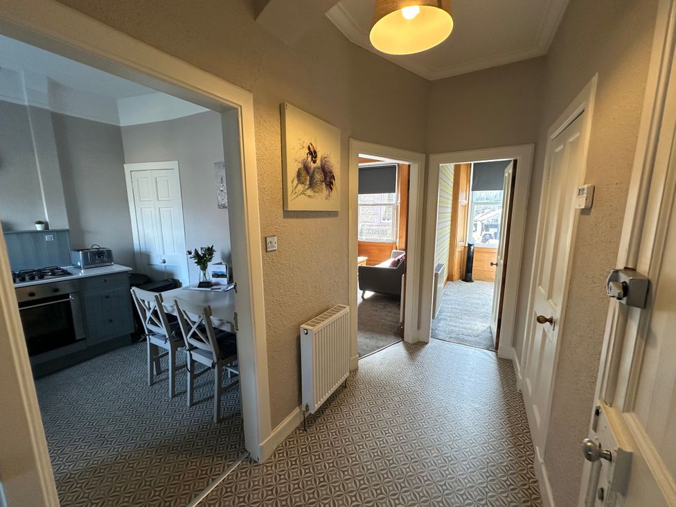 A hallway with a view towards a kitchen and dining area at The Tweed in Melrose