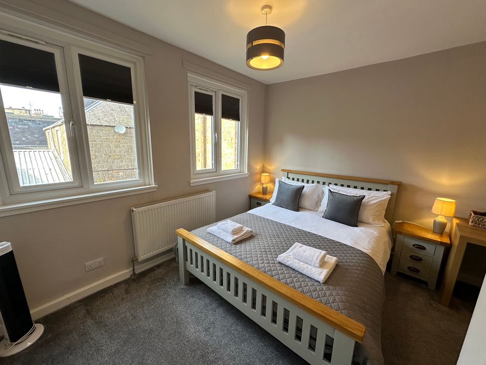 A bedroom with a bed and windows at The Esk in Melrose