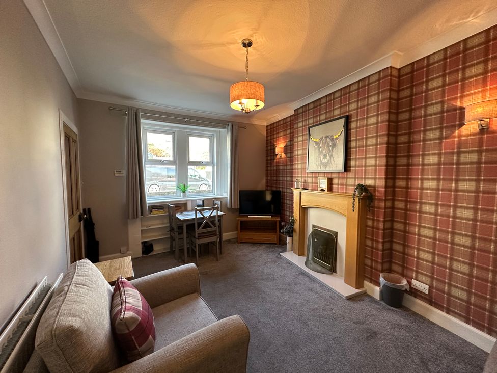 A living room with a sofa, table, and television at Pergola in Melrose