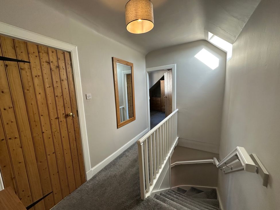A hallway with a staircase and wooden door at Pergola in Melrose