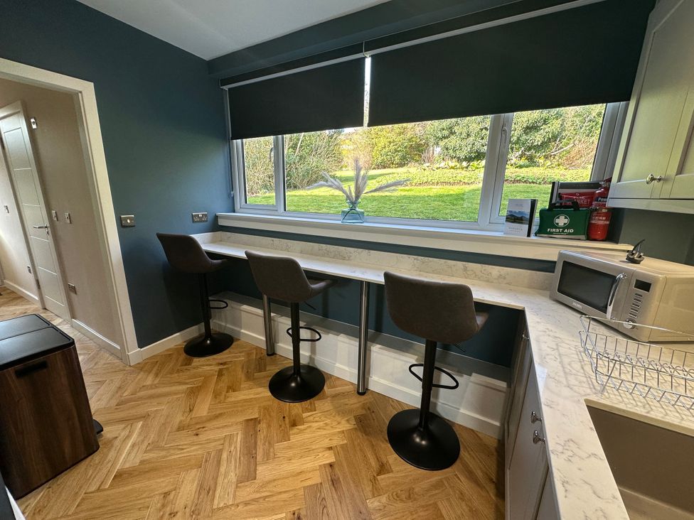 A kitchen with bar stools and a window at Broombank in Melrose