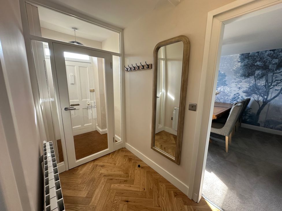 A hallway with a mirror and coat hooks at Broombank in Melrose