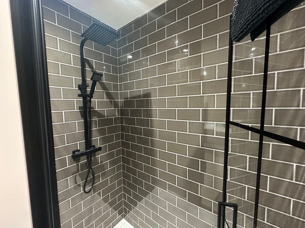 A shower with tiled walls and modern fixtures at Broombank in Melrose