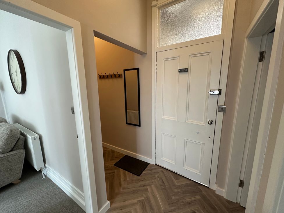A hallway with a clock, mirror, and coat hooks at Horsemarket in Kelso