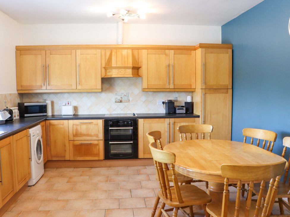 A kitchen with wooden cabinets and a dining table at BREAGHMORE