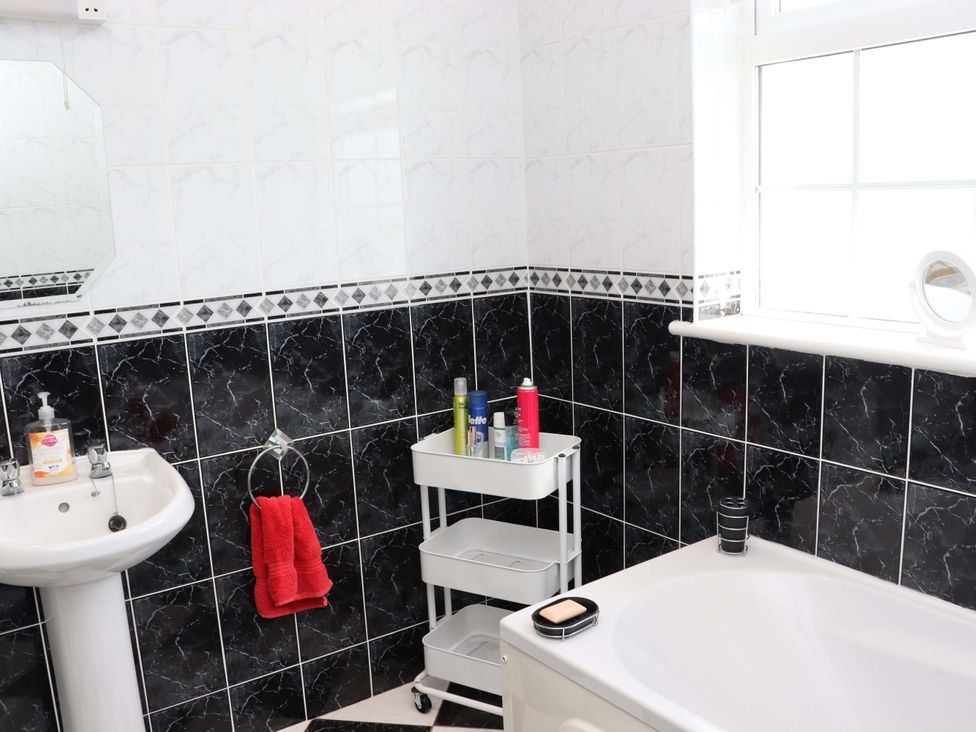 A bathroom featuring a wash basin, bathtub, and storage cart at BREAGHMORE