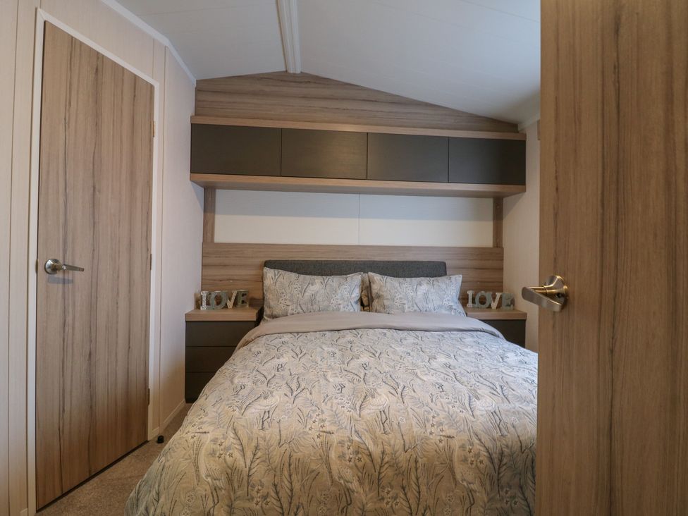 A bedroom with a bed and shelves at no 20 Barley Way in Colchester