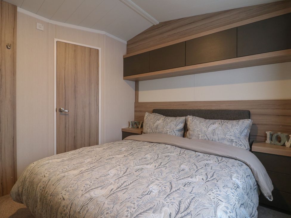 A bedroom with a double bed and wood fixtures at no 20 Barley Way in Colchester