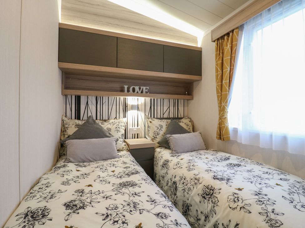 A bedroom with two beds and a decorative shelf at no 20 Barley Way Colchester