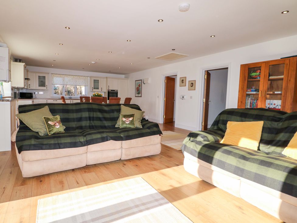 A living room with sofas and kitchen area at Snowdrop Cottage in Maidstone