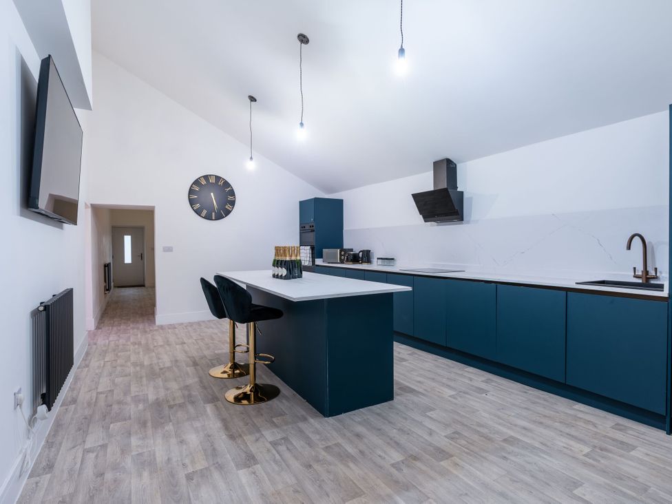 A kitchen with a kitchen island and bar stools at Manor Farm in Glastonbury