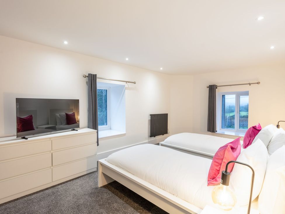 A bedroom with two beds and a television at Manor Farm in Glastonbury