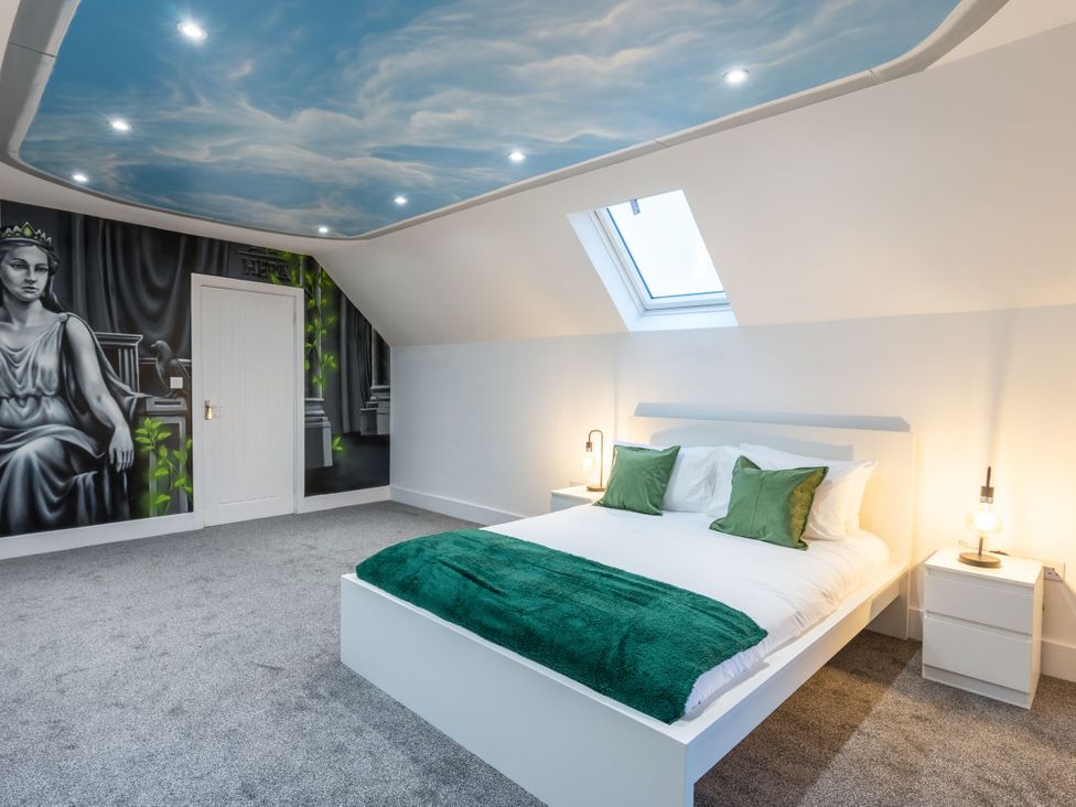 A bedroom with a bed, bedside table and wall mural at Manor Farm in Glastonbury