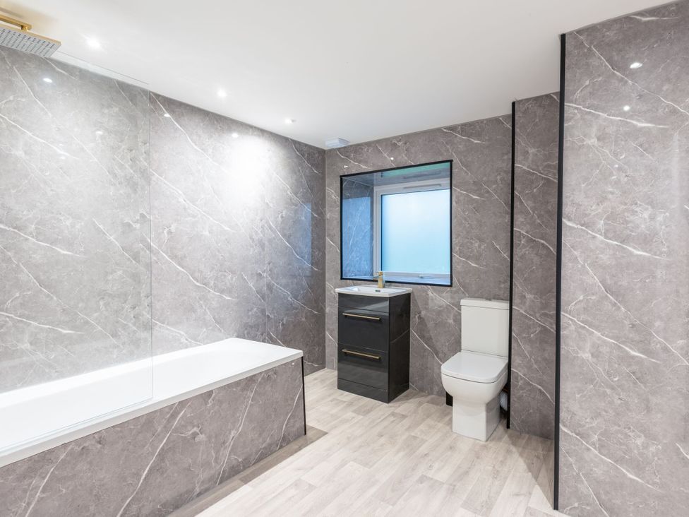A bathroom with a bathtub, toilet, vanity and window at Manor Farm in Glastonbury