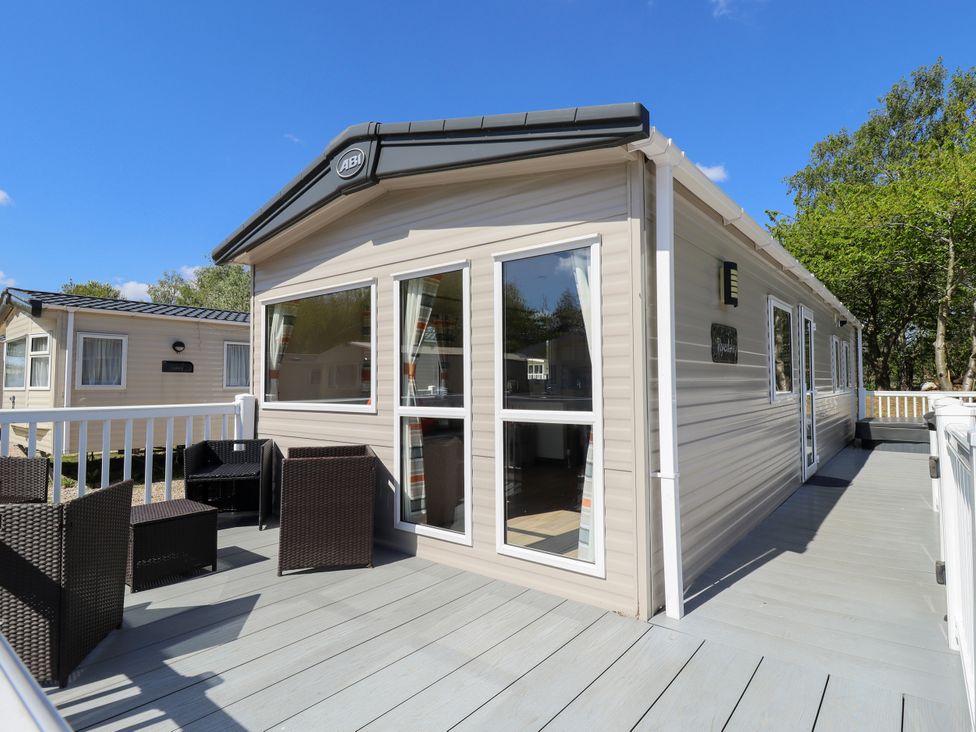 A caravan with a deck and chairs at 39 Larch View with hot tub Tattershall