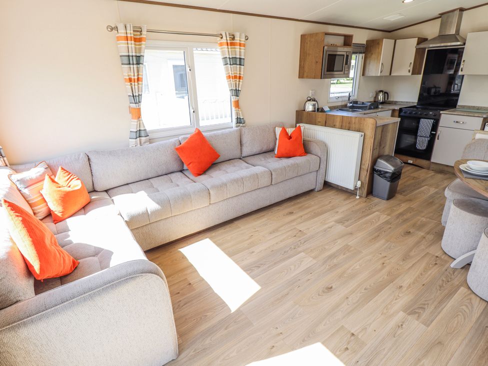 A living room with a sofa and kitchen area at 39 Larch View with hot tub Tattershall