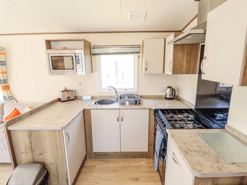 A kitchen with appliances including a microwave and toaster at 39 Larch View with hot tub in Tattershall