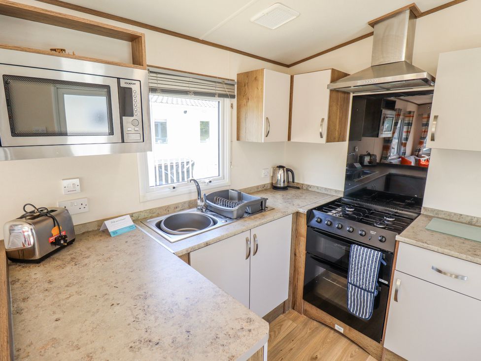 A kitchen with appliances and sink at 39 Larch View with hot tub Tattershall