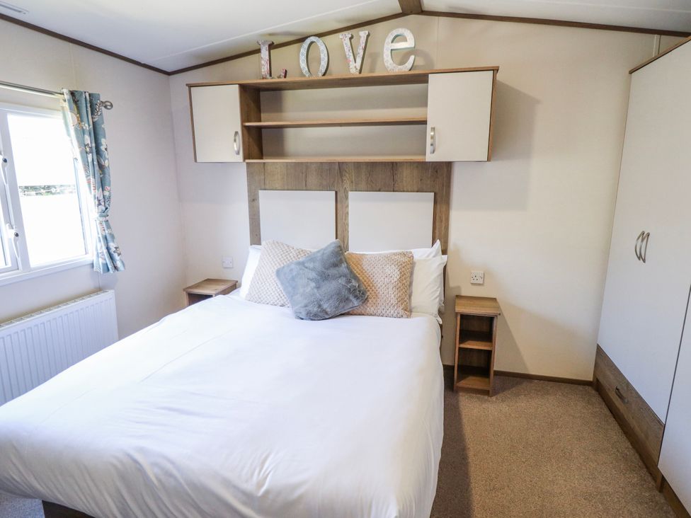 A bedroom with a bed and storage at 39 Larch View with hot tub Tattershall