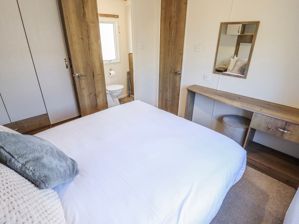 A bedroom with a bed and wardrobe at 39 Larch View with hot tub Tattershall