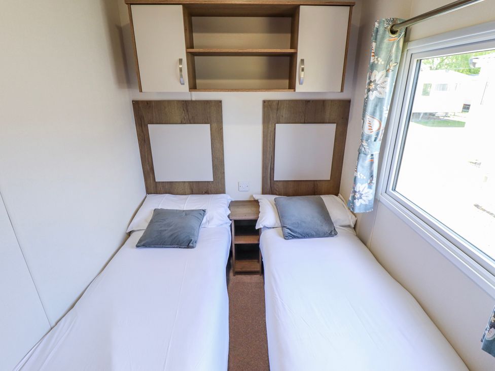 A bedroom with twin beds and a window at 39 Larch View with hot tub Tattershall