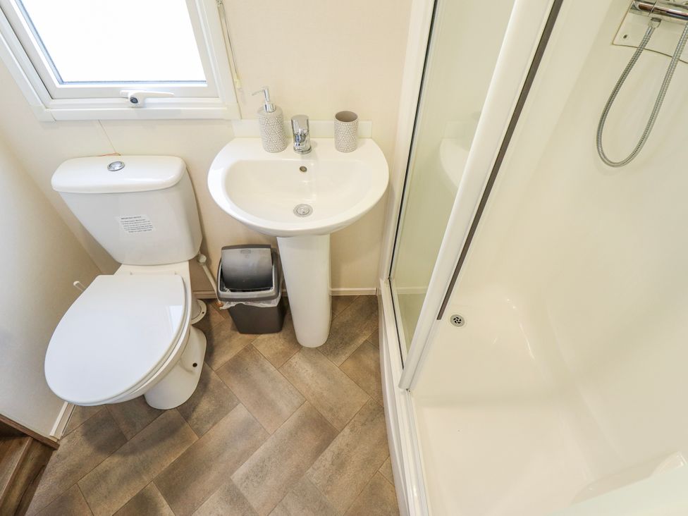 A bathroom with a toilet, sink, and shower at 39 Larch View with hot tub, Tattershall